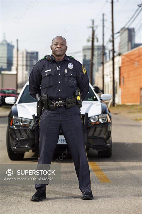 A Police Officer Standing In Front Of A Gate With His Cell Phone On His